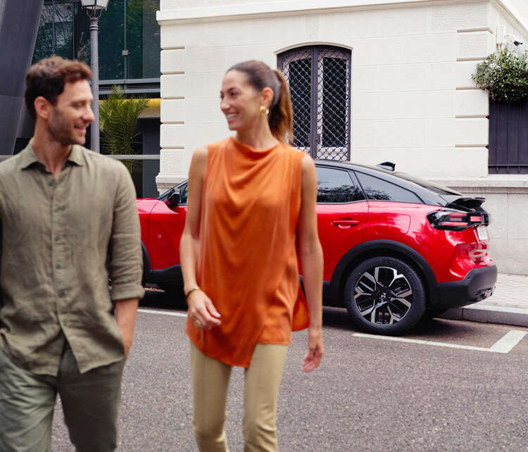 Чоловік і жінка відходять від червоного Citroën C4 у місті